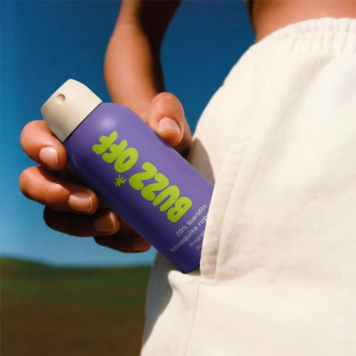 Hand pulling a purple BuzzOff can from a pocket
