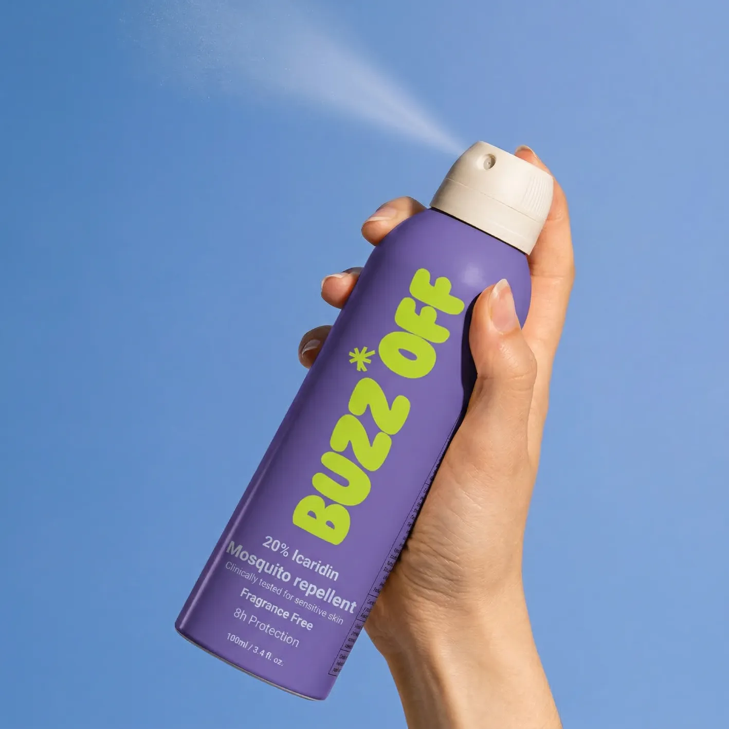 Hand spraying a purple BuzzOff can against a blue sky