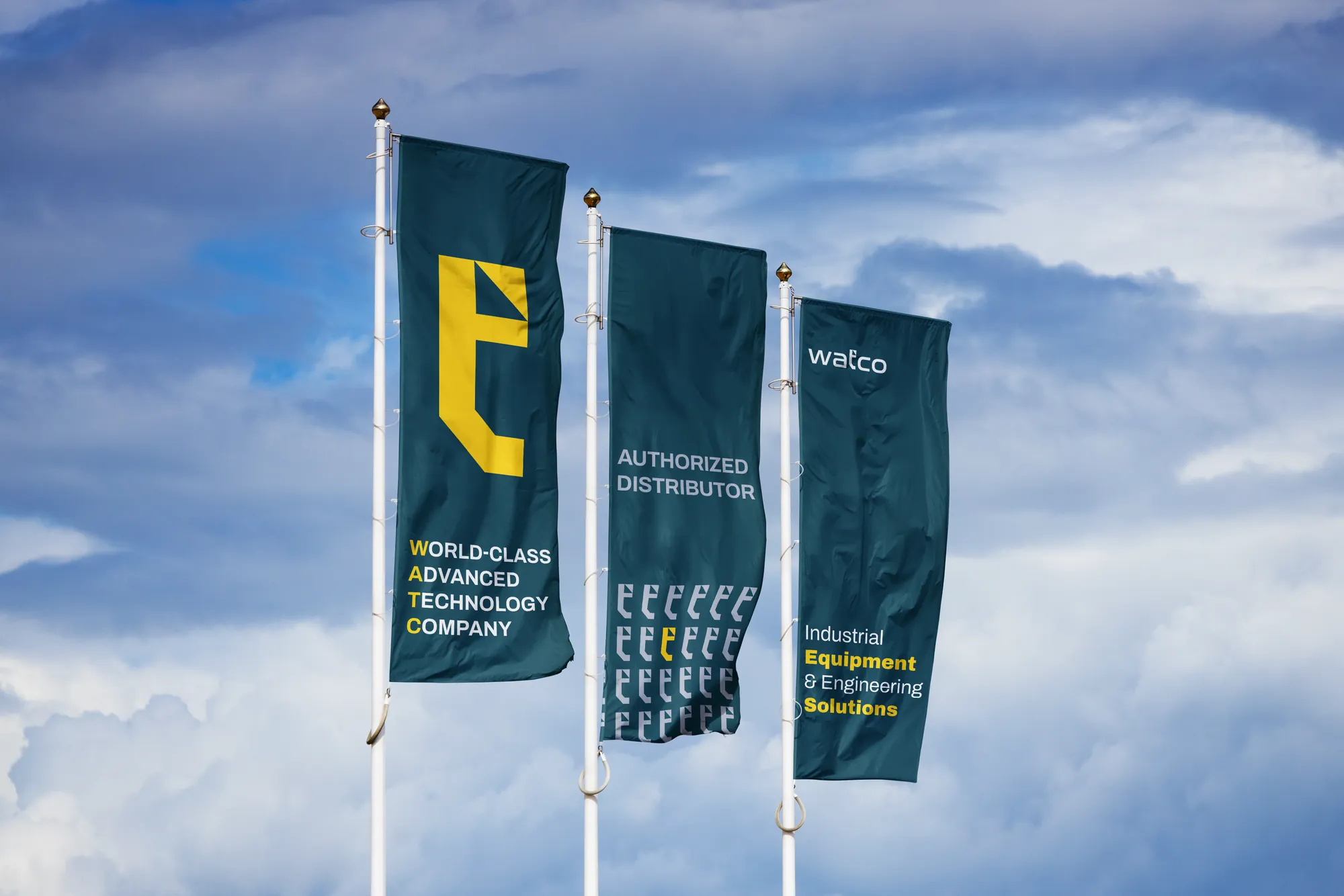 Three teal Watco feather flags against the sky