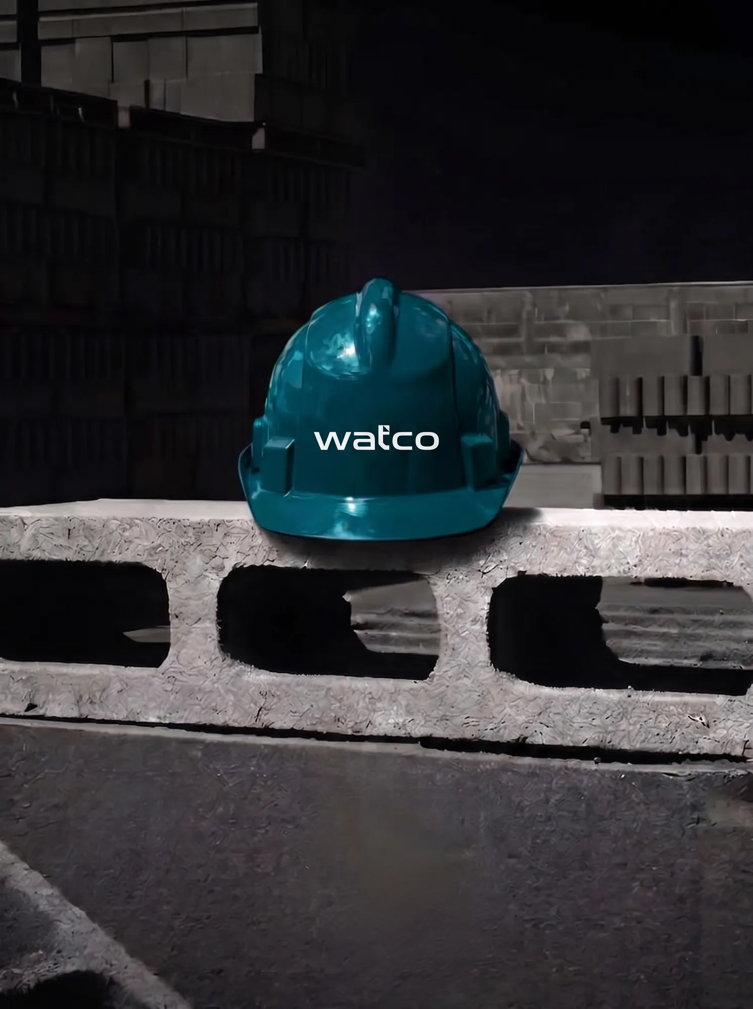 Teal Watco hard hat resting on a concrete block