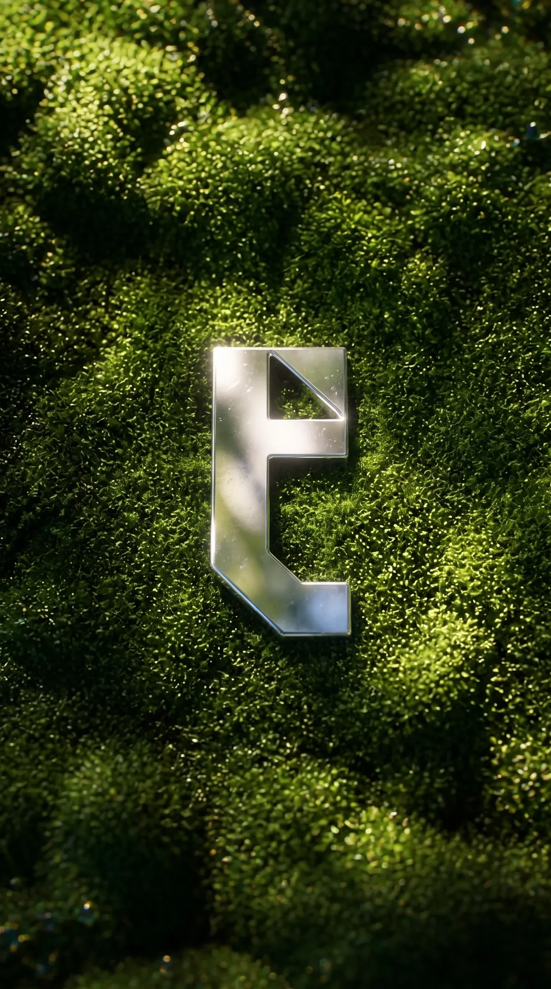 Metallic t icon set into green moss